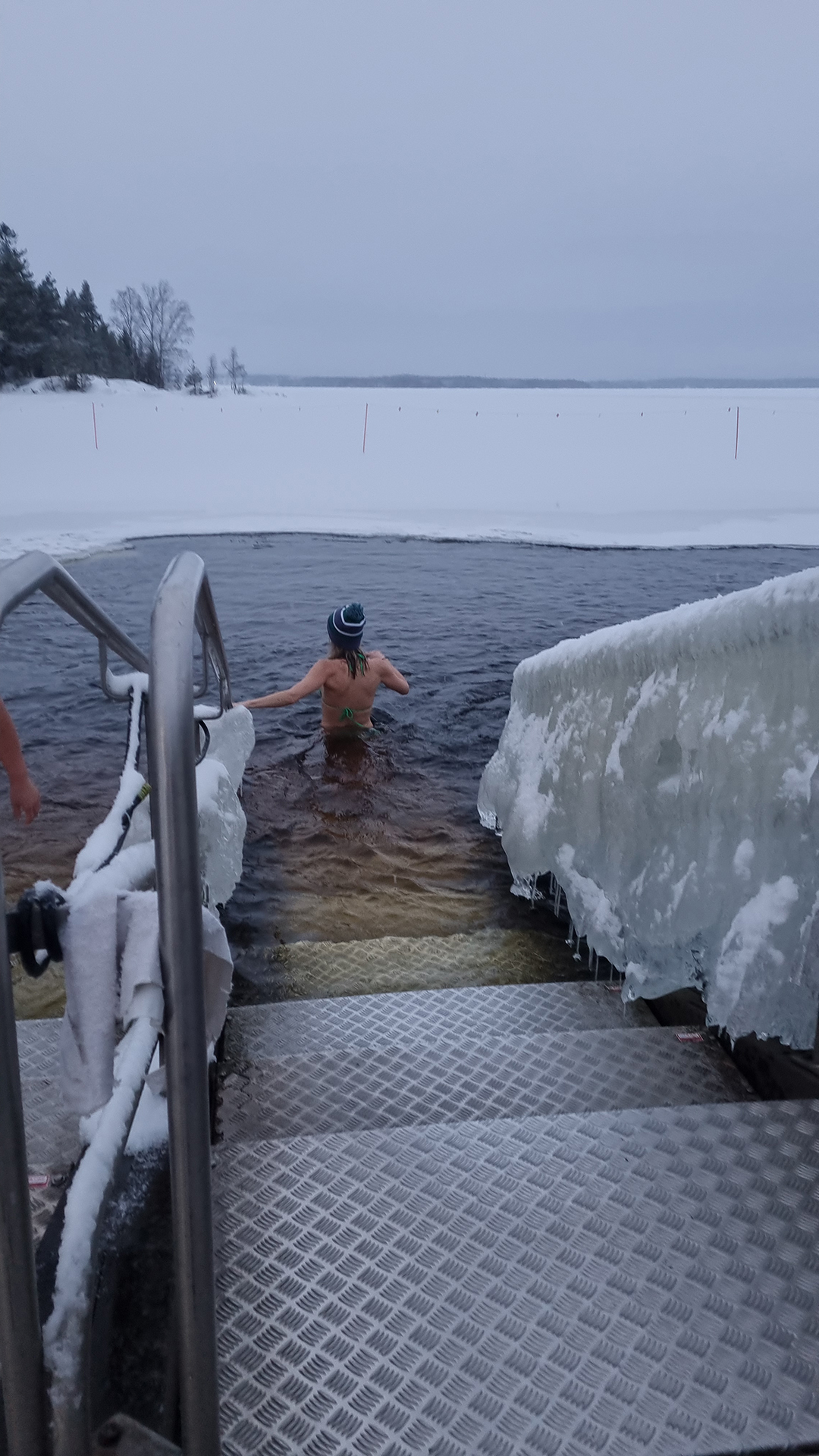 A person entering an icy lake after sauna, a signature Finnish winter tradition.
