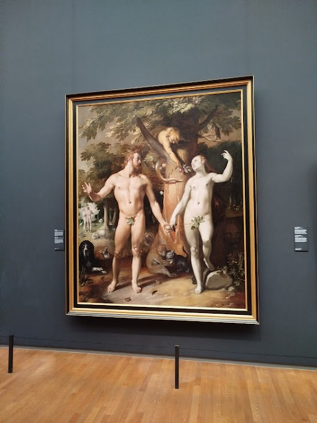 Gallery room in the Rijksmuseum with a large classical painting and visitors in Amsterdam.