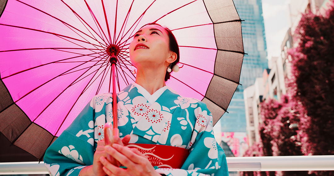 Ženska v tradicionalnem japonskem kimonu z rožnatim papirnatim dežnikom.