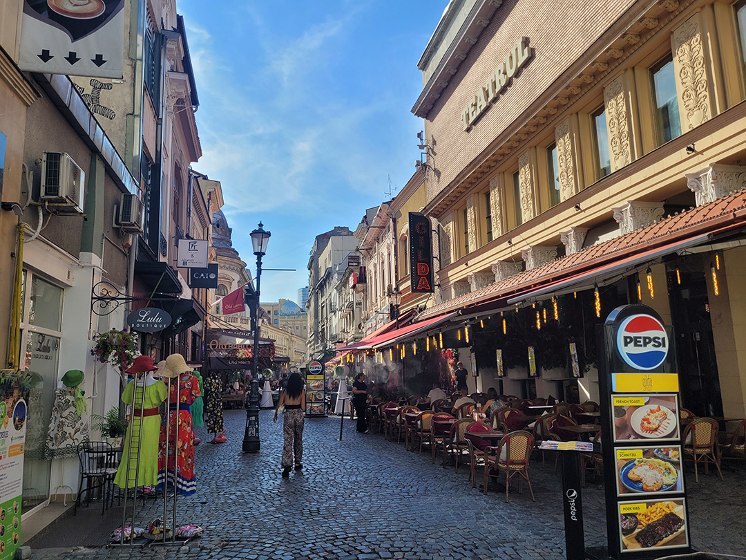 Živahna tlakovana ulica z restavracijami in lokali v starem mestnem jedru Bukarešte.