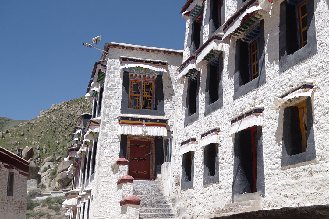 Tradicionalne bele samostanske stavbe Drepunga z značilnimi tibetanskimi okni in barvitimi arhitekturnimi detajli.